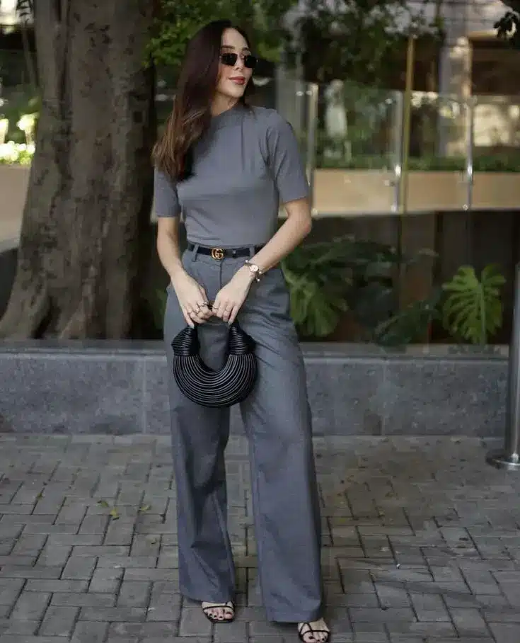 Look cinza Mulher usando look cinza monocromático com calça pantalona e blusa de manga curta em ambiente urbano.