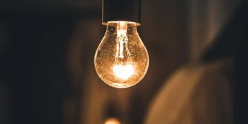 Lâmpada acesa em ambiente escuro simbolizando o novo programa Luz do Povo,