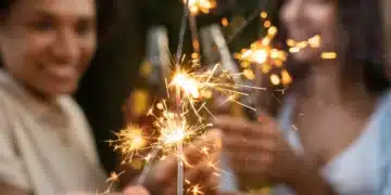Pessoas comemorando com velas de bengala acesas durante as festas de fim de ano.