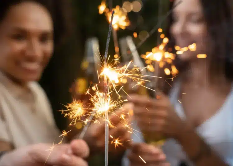 Pessoas comemorando com velas de bengala acesas durante as festas de fim de ano.