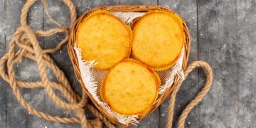 Três broas redondas de fubá com queijo dentro de uma cesta rústica, prontas para servir, destacando a cor amarelada e o aspecto caseiro.