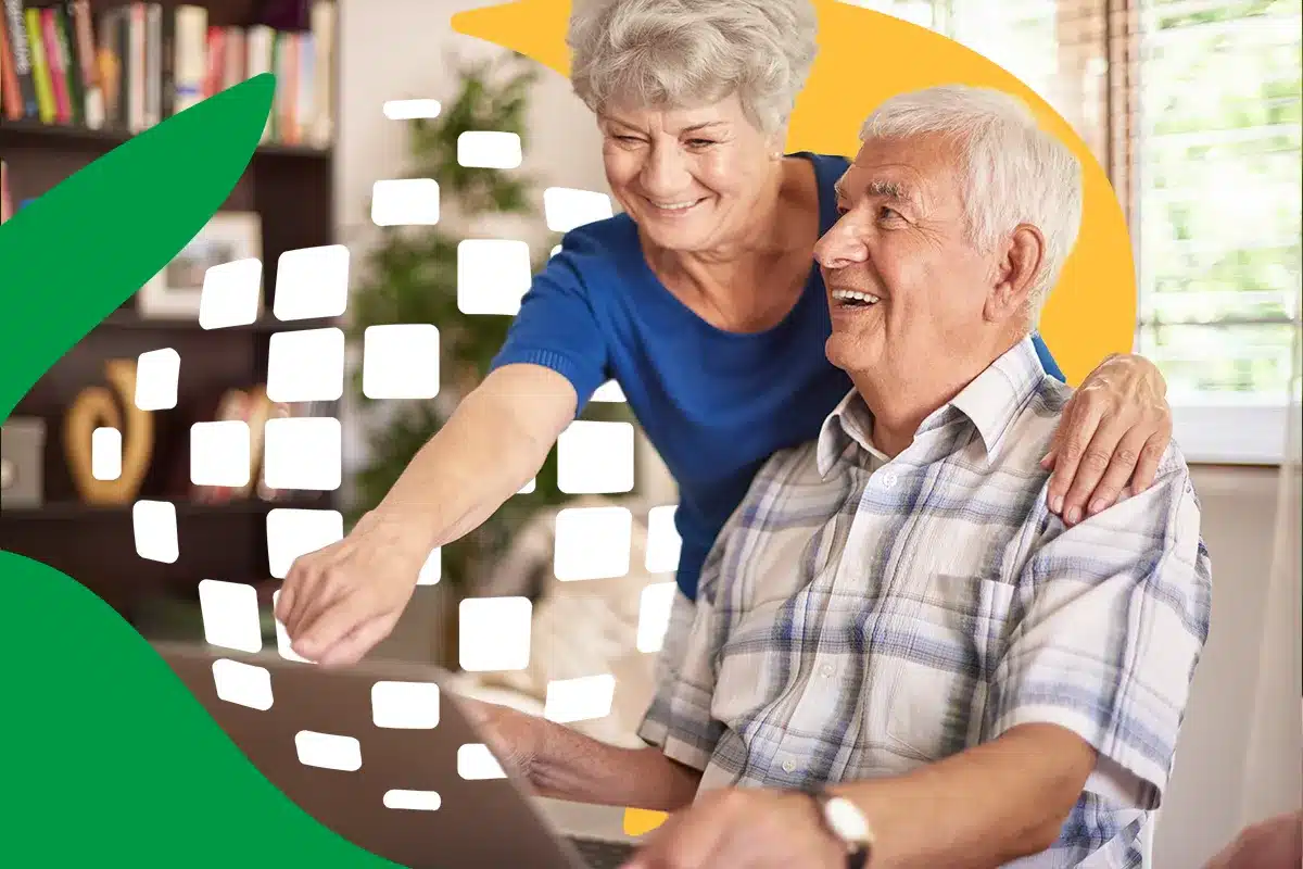 consulta online extrato meu inss Um casal de idosos sorridentes em casa operando um notebook para consultar o extrato de pagamento do benefício previdenciário.