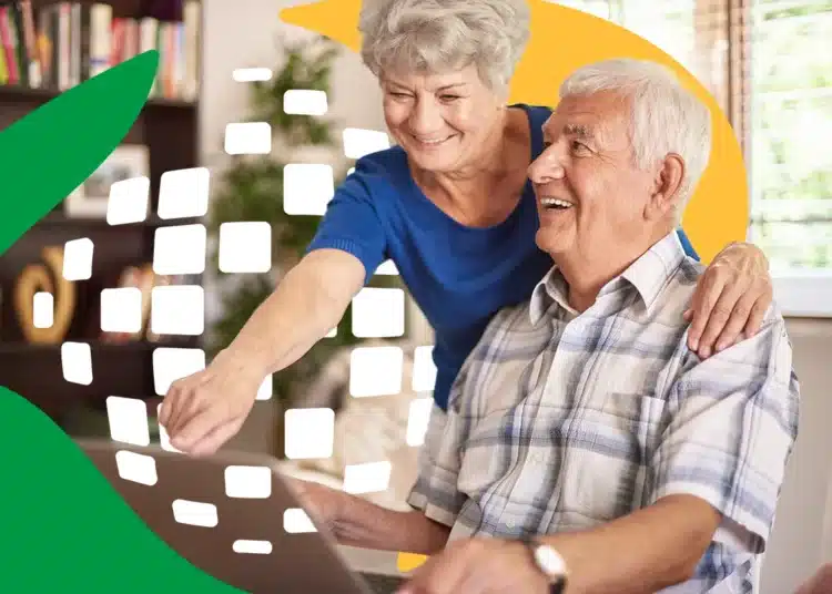 Casal de idosos felizes usando um laptop com orientação em ambiente doméstico