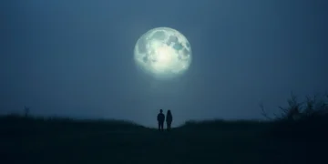 Casal observando uma lua gigante em meio à neblina ao anoitecer.