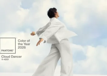 Pessoa vestindo roupas brancas posando diante de um céu suave, ilustrando a cor Pantone Cloud Dancer, eleita a cor de 2026.