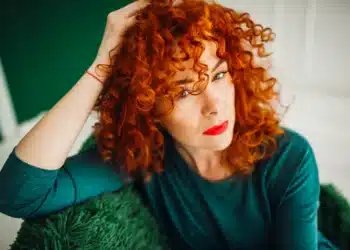 Mulher com cabelos ruivos cacheados exibindo corte moderno que é tendência para 2026.