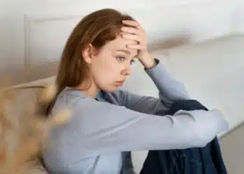 Mulher com expressão de preocupação, refletindo sobre o desgaste emocional e como fortalecê-lo com ferramentas psicológicas.