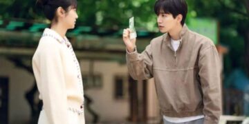 Cena de Cashero, com o protagonista mostrando uma nota de dinheiro para a personagem feminina, em um cenário ao ar livre.