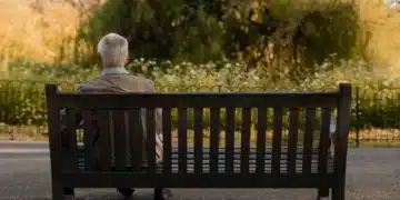 Idoso sentado sozinho em um banco de parque, simbolizando o medo da solidão na terceira idade.