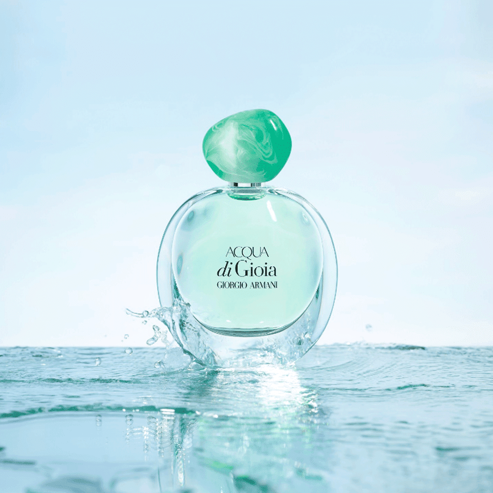 Frasco de perfume feminino Acqua di Gioia da Giorgio Armani, com tampa verde-esmeralda, em um cenário aquático com respingos de água.