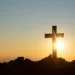Imagem de uma cruz contra o pôr do sol, simbolizando fé e esperança para o domingo.