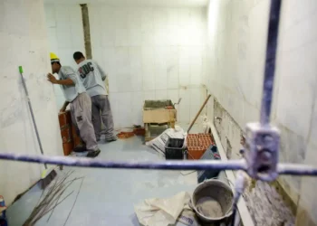 Homem segurando cofrinho rosa e notas de 100 reais, promovendo poupança para ensino médio