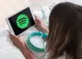 Pessoa utilizando tablet com o logo do Spotify enquanto prepara fones de ouvido, representando a divulgação dos álbuns mais ouvidos de 2025.
