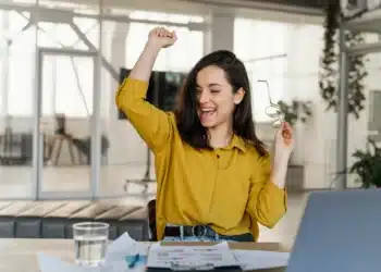 Mulher comemorando conquista profissional em ambiente de trabalho moderno, simbolizando sucesso em 2026.