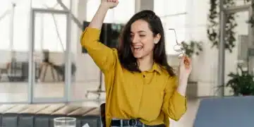 Mulher comemorando conquista profissional em ambiente de trabalho moderno, simbolizando sucesso em 2026.