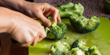 Close-up de ramos de brócolis frescos e verdes dispostos sobre uma tábua de madeira, destacando sua textura e cor vibrante como símbolo de alimentação saudável.