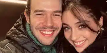 Selfie em close dos atores turcos Aytaç Şaşmaz e Cemre Baysel sorrindo e encostando os rostos. Aytaç usa uma jaqueta preta com gola alta de lã verde e Cemre veste uma blusa preta de gola alta.