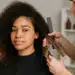 Cabeleireira cortando o cabelo de uma jovem com cabelo cacheado