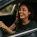 Jovem mulher sorrindo enquanto dirige um carro,