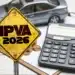 Placa amarela escrita IPVA 2026, ao lado de calculadora, moedas e carro em miniatura..