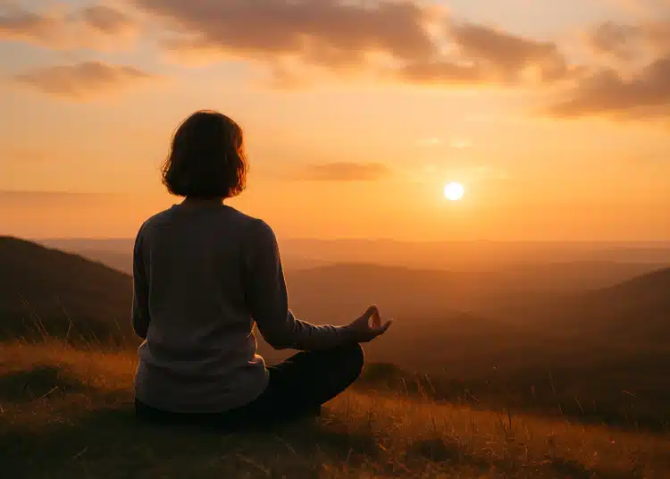 Pessoa meditando ao pôr do sol em uma paisagem de montanhas
