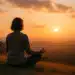 Pessoa meditando ao pôr do sol em uma paisagem de montanhas