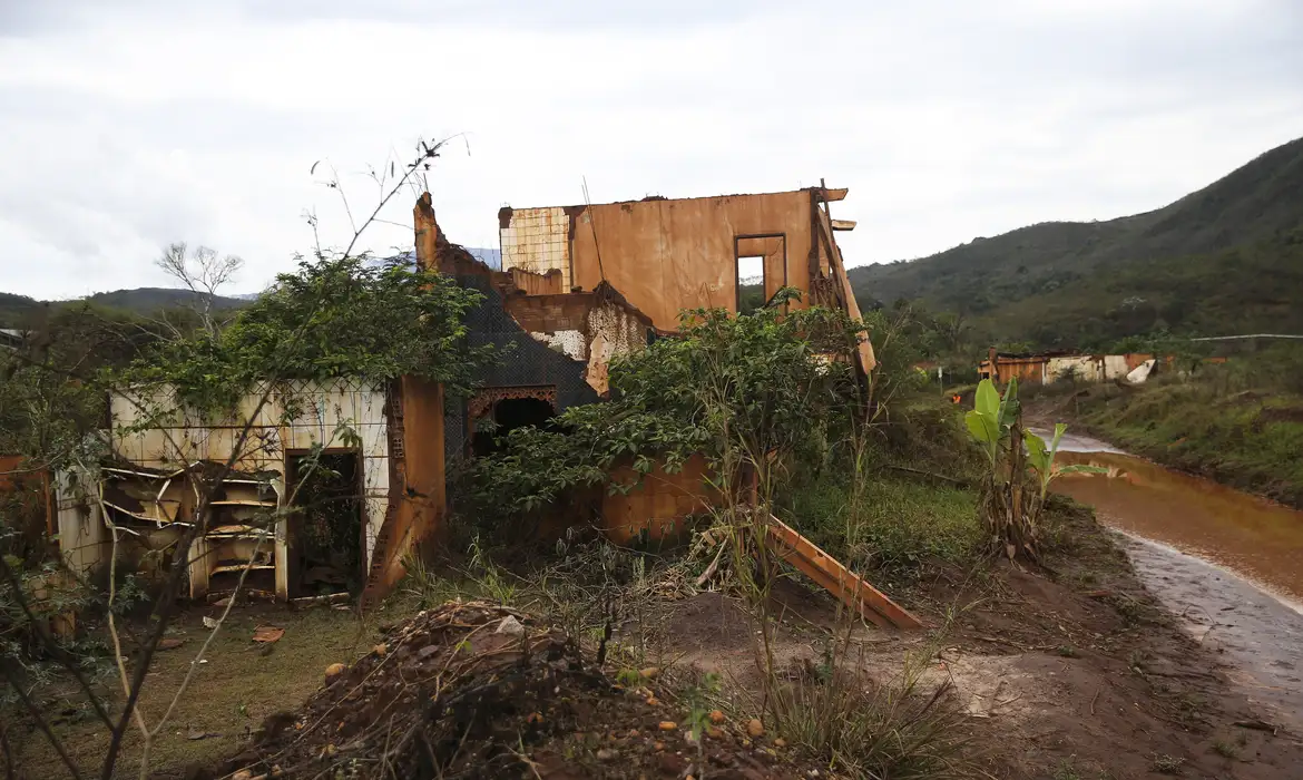 Ruínas de casa após desastre ambiental em 2026 Casa destruída e tomada pelo mato ao lado de estrada barrenta em área rural, 2026