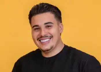 Ex-participante sorrindo para a câmera com fundo amarelo.