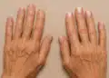 Mãos femininas com unhas naturais e unhas pintadas com esmalte nude