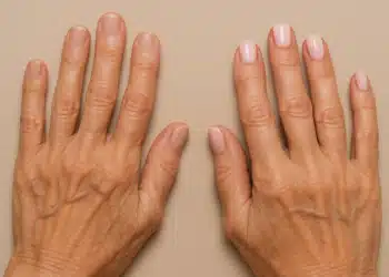 Mãos femininas com unhas naturais e unhas pintadas com esmalte nude