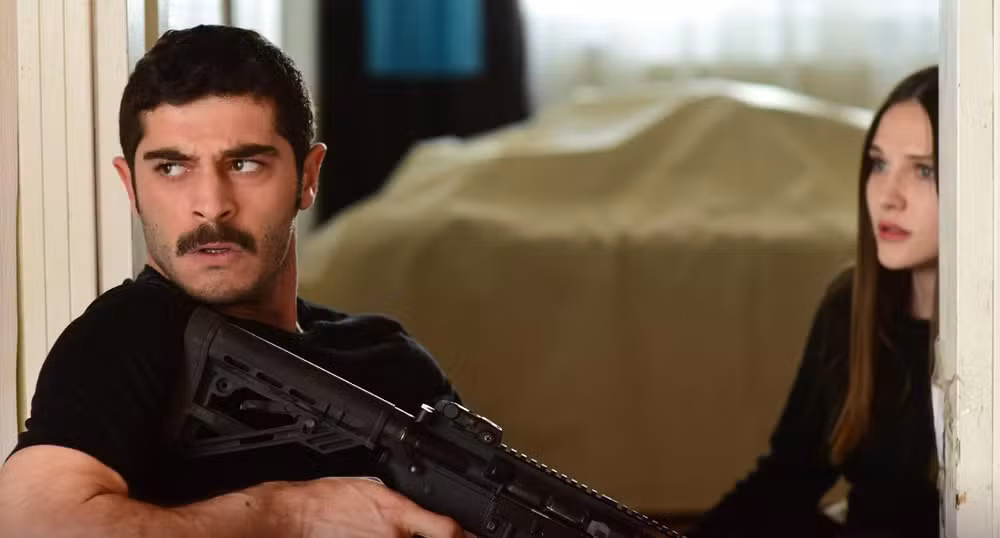 Marasli – Amor e proteção em meio ao perigo Protagonistas da série turca Marasli em cena tensa, representando ação, romance e mistério.