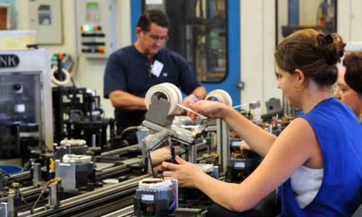 Trabalhadores na indústria em linha de produção moderna Funcionários operam máquinas em linha de produção industrial em 2026