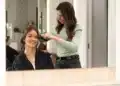 Mulher sorrindo enquanto recebe tratamento de cabelo em um salão de beleza.
