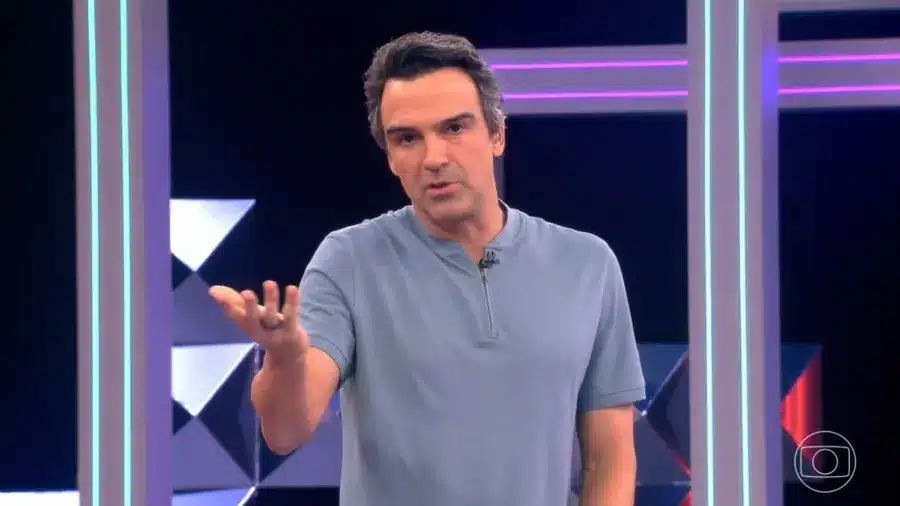 Apresentador conduz anúncio do paredão em reality nesta sexta Apresentador gesticulando com uma mão estendida durante fala em estúdio iluminado